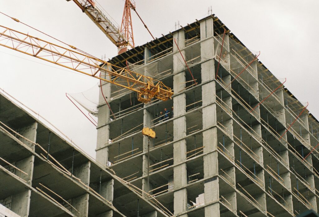 Crane near concrete buidling under construction showing construction cost overruns.
